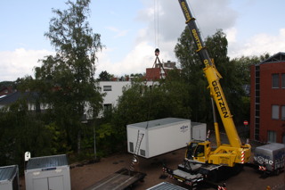 Per Kran werden die Container auf ihre richtige Position gesetzt.